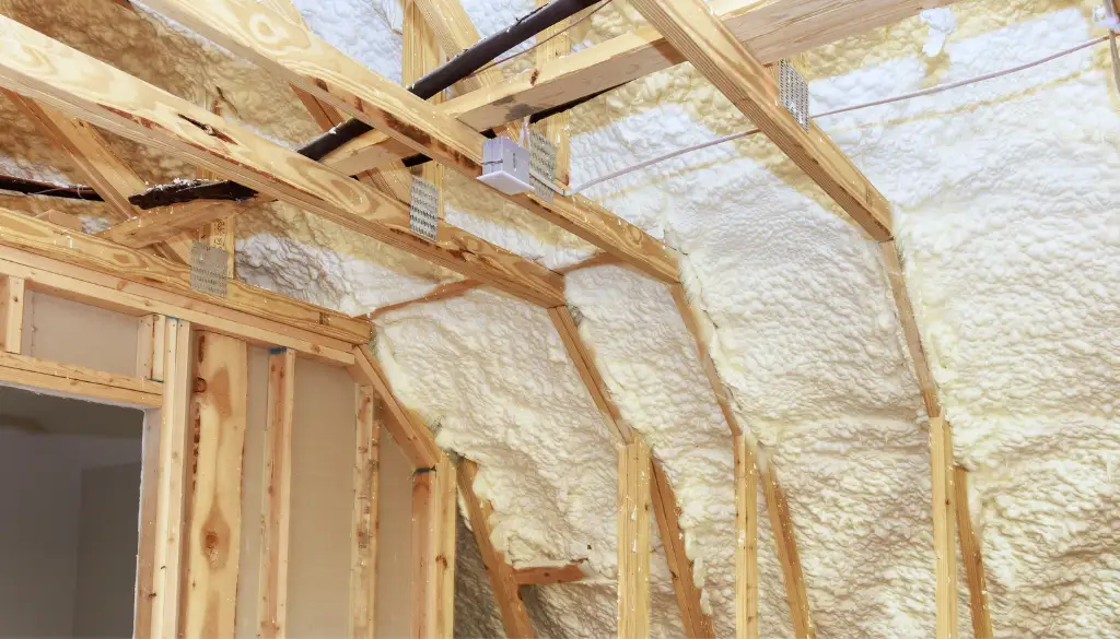 Commercial building spray foam insulation applied to curved ceiling and wooden trusses
