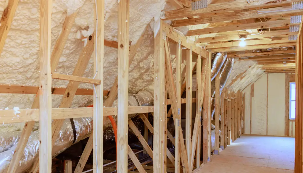 Crawl space spray foam insulation applied to ceiling and walls with exposed ductwork in a residential building.